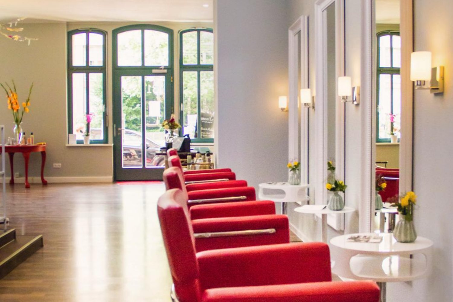 Der Salon von Miss Lilly’s mit roten Sesseln, hohen Fenstern und viel Licht